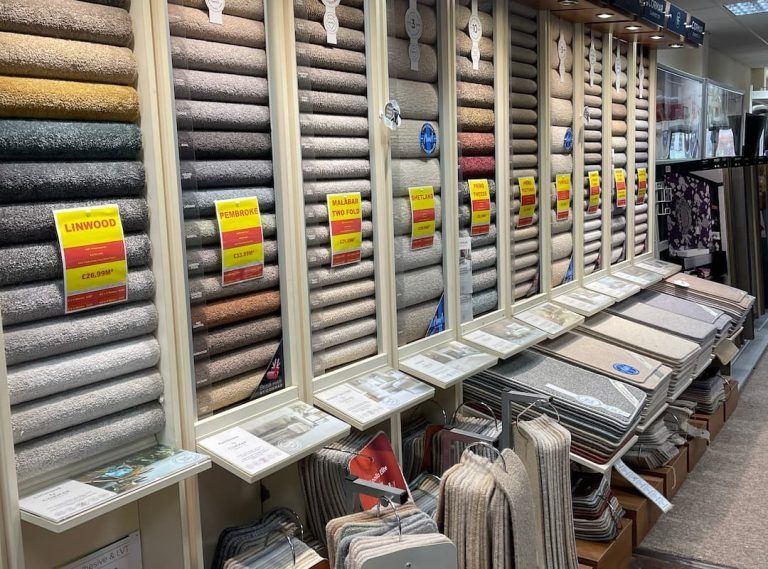 A carpet store display showcasing various carpet rolls and samples, many on sale.