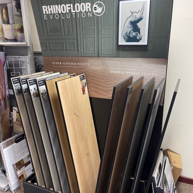 Display of RhinoFloor Evolution flooring samples in a store; various wood-look planks.