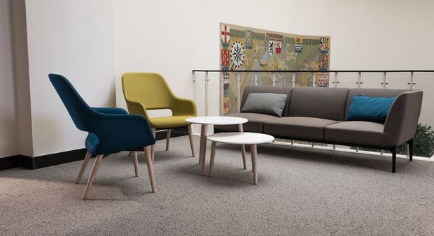Living room with gray sofa, teal chair, yellow chair, white tables, and rug art.