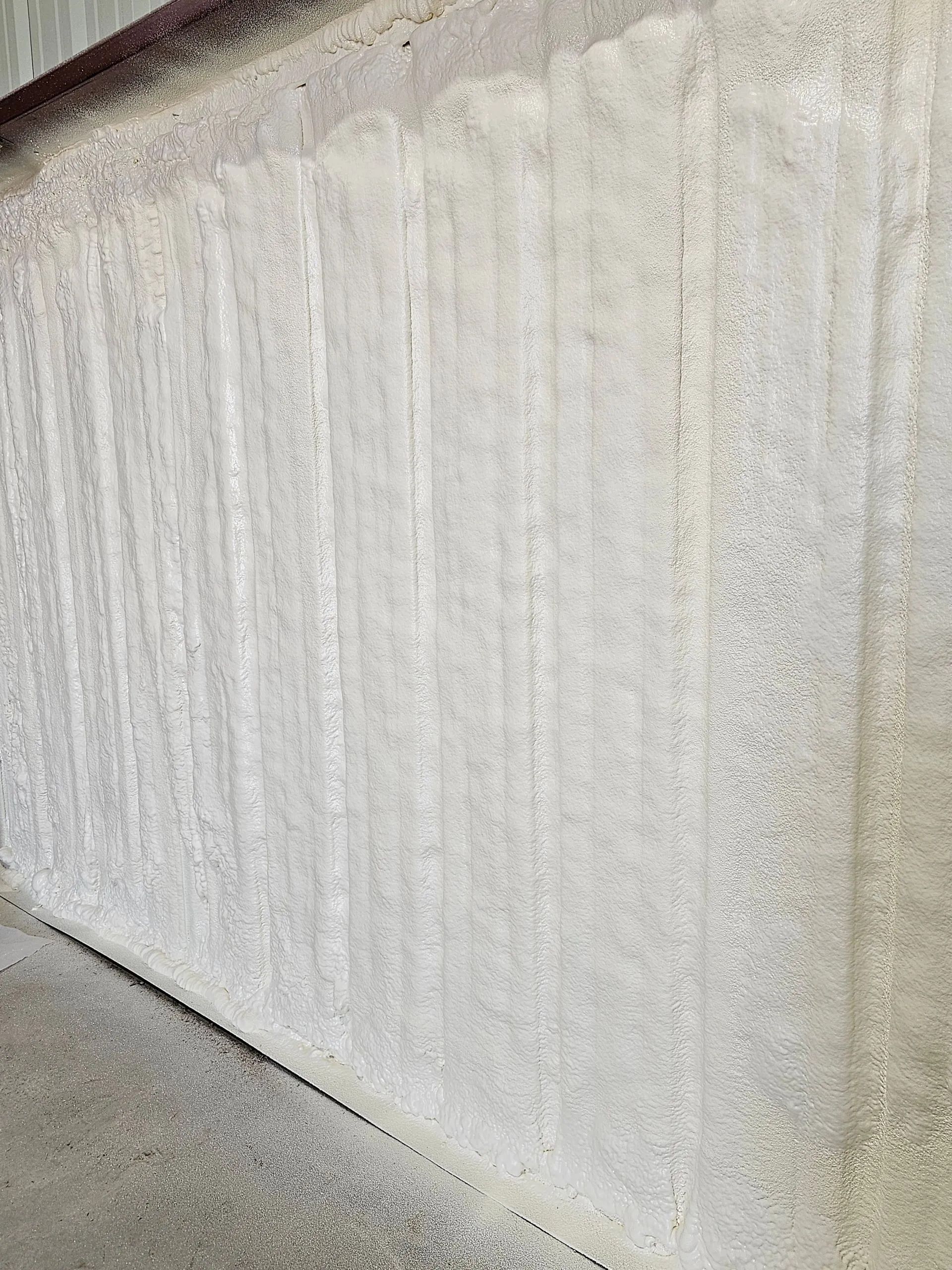 A close-up view of an off-white wall texture featuring prominent, uniform vertical ridges or grooves.