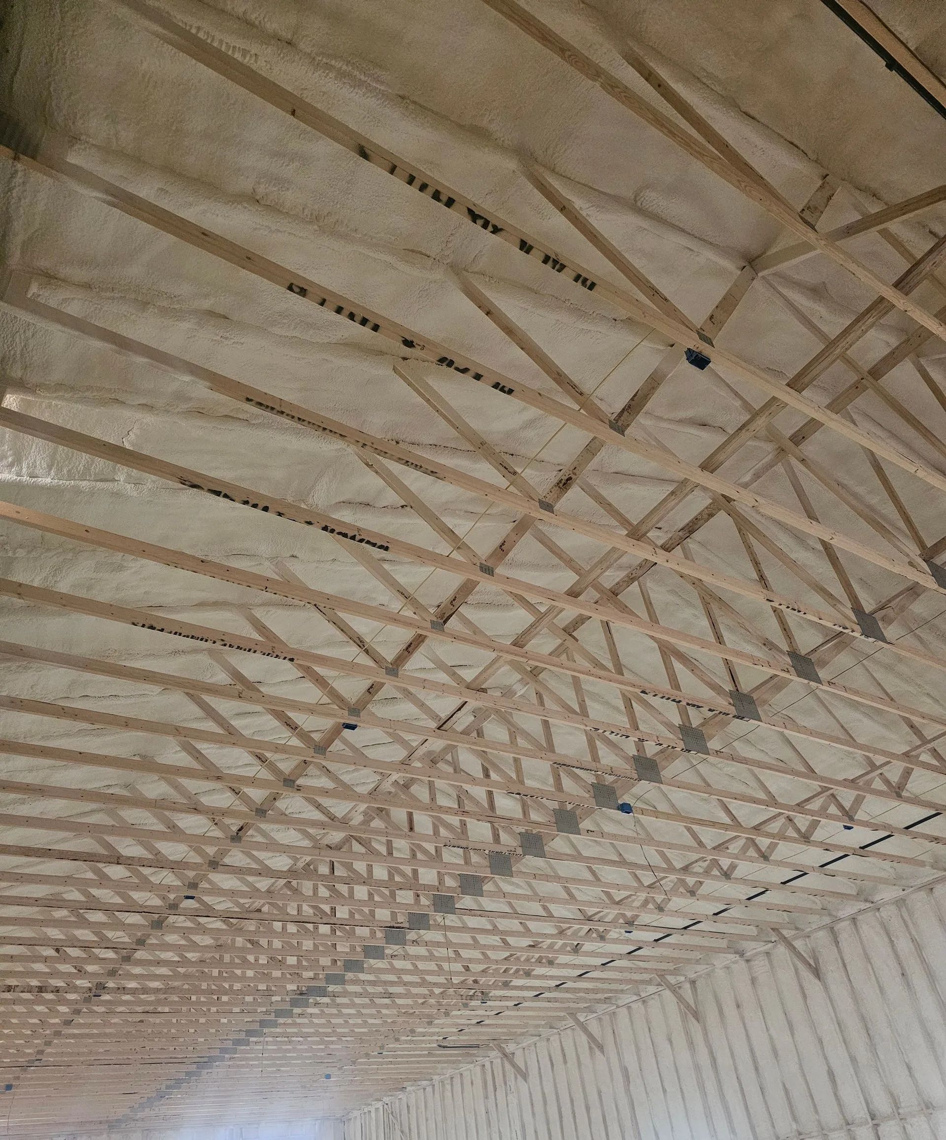 A low-angle view of a beige, ribbed concrete ceiling featuring a geometric, intersecting grid of wooden support beams.
