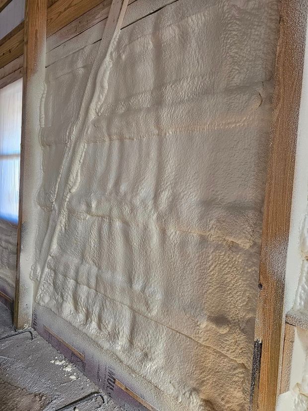 Close-up of a large mesh-covered wall or tarp, framed by wood, with gravel below.