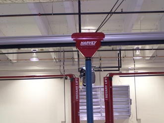 Red Harvey oil drain funnel above a Rotary Lift in a garage.