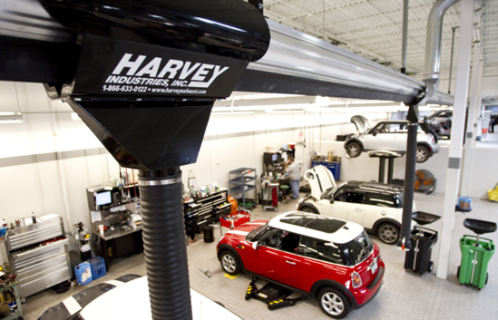 Overhead view of a car repair shop featuring a red Mini Cooper on a lift and a Harvey Industries system.