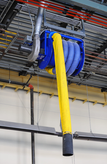 Blue and yellow industrial hose reel suspended from a factory ceiling, likely for fume extraction.
