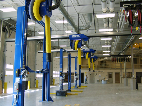 Blue car lifts in a well-lit shop with yellow flexible hoses attached.