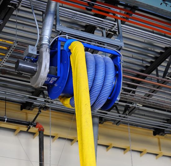 Blue and yellow retractable hose system mounted on an industrial ceiling, likely for dust extraction or similar.