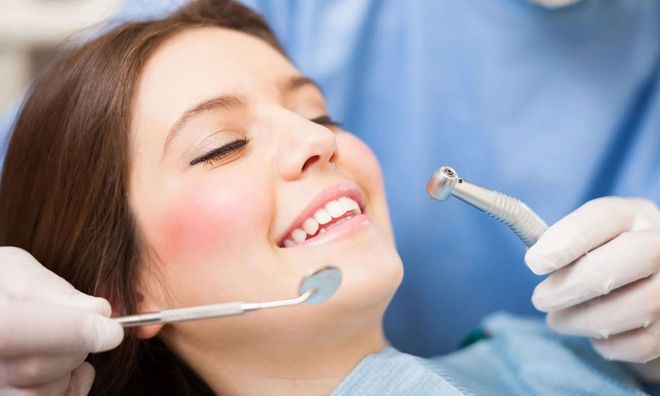 A woman is getting her teeth examined by a dentist.