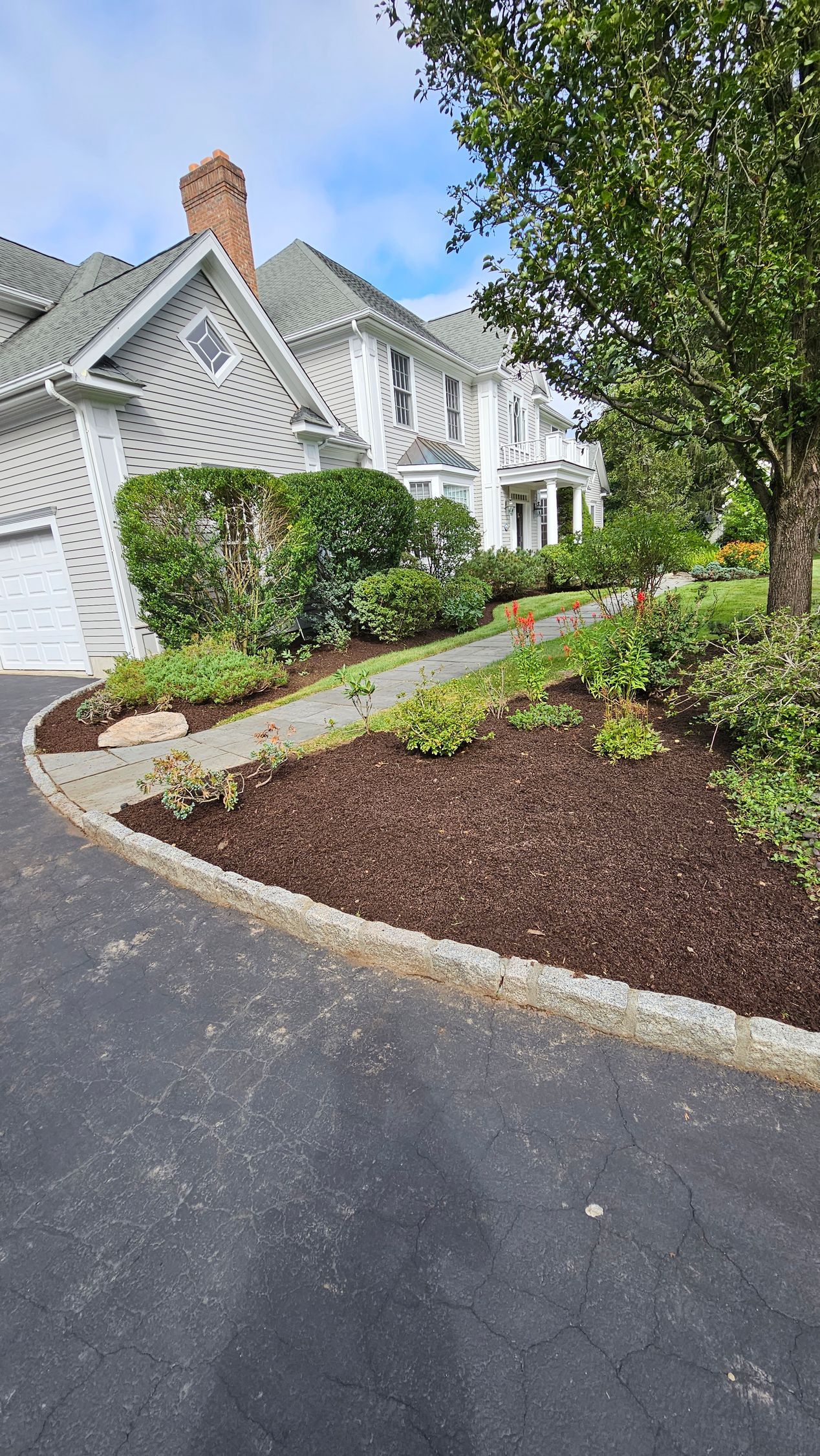 A large white house with a driveway leading to it.