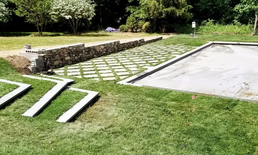 A large lawn with a swimming pool in the middle of it.