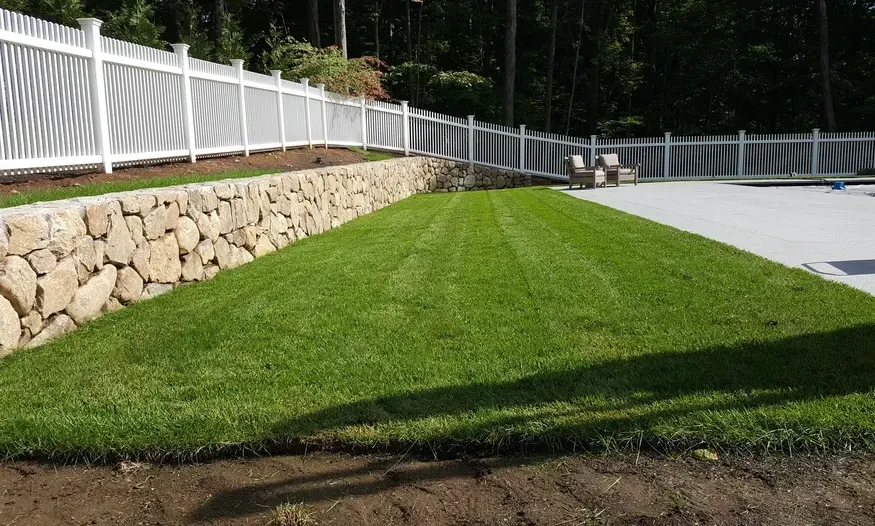 A white picket fence surrounds a lush green lawn.
