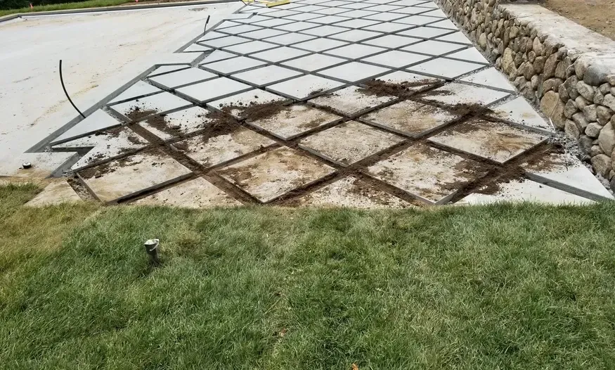 A concrete walkway is being built next to a stone wall.