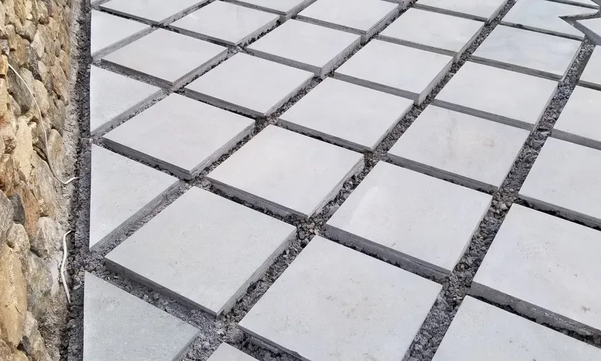 A concrete walkway with a stone wall in the background