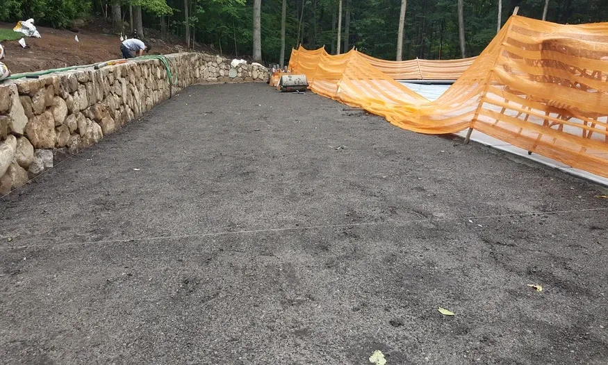A large pile of dirt is sitting in front of a stone wall.