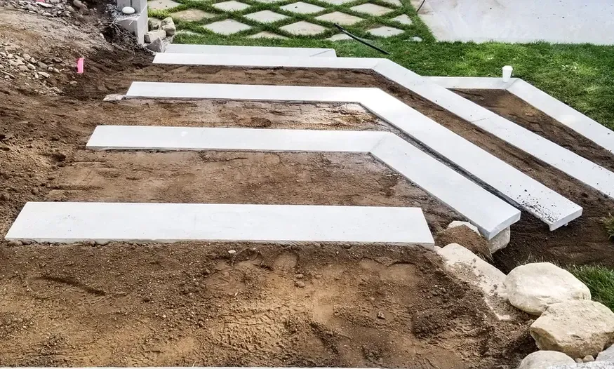 A concrete walkway is being built in the dirt.