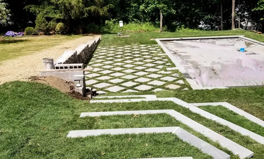 A concrete walkway leading to a swimming pool in a backyard.