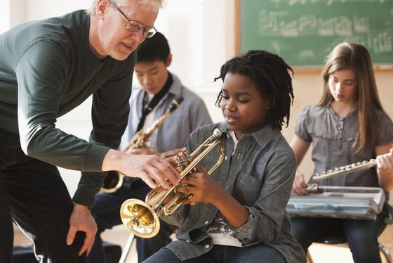 Music instructor teaching a young boy how to play the trumpet