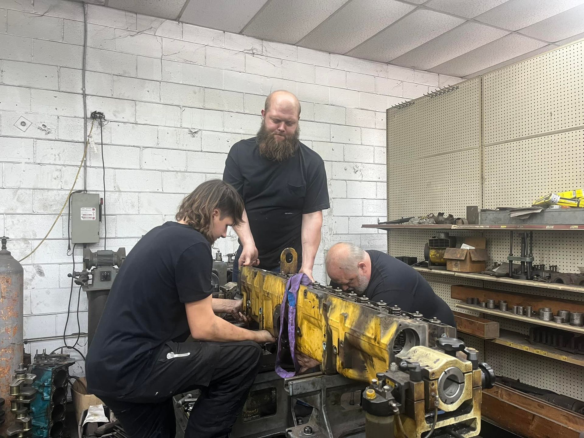 Three men are working on a machine in a garage.