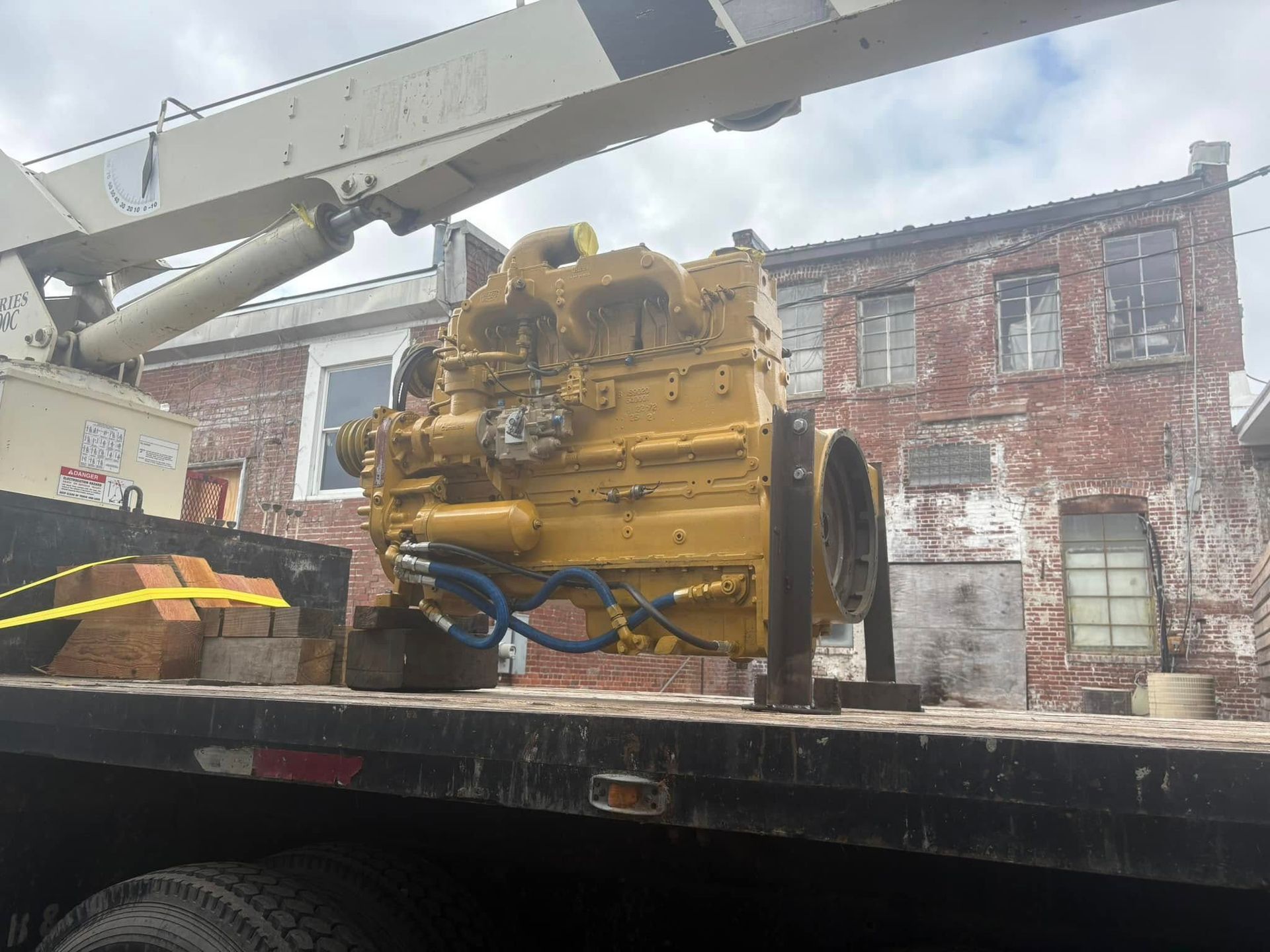 A large yellow engine is sitting on top of a flatbed truck.