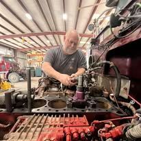 A man is working on the engine of a truck in a garage.
