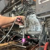 A person is working on a car engine in a garage.