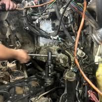 A man is working on a car engine with a wrench.