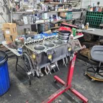 A engine block is sitting on top of a red stand in a garage.