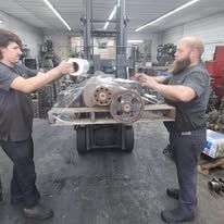 Two men are working on a machine in a garage.