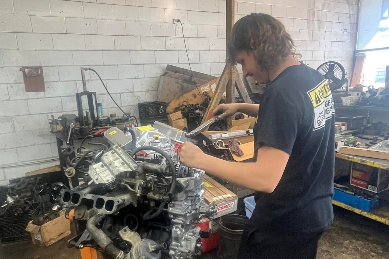 A man is working on a car engine in a garage.