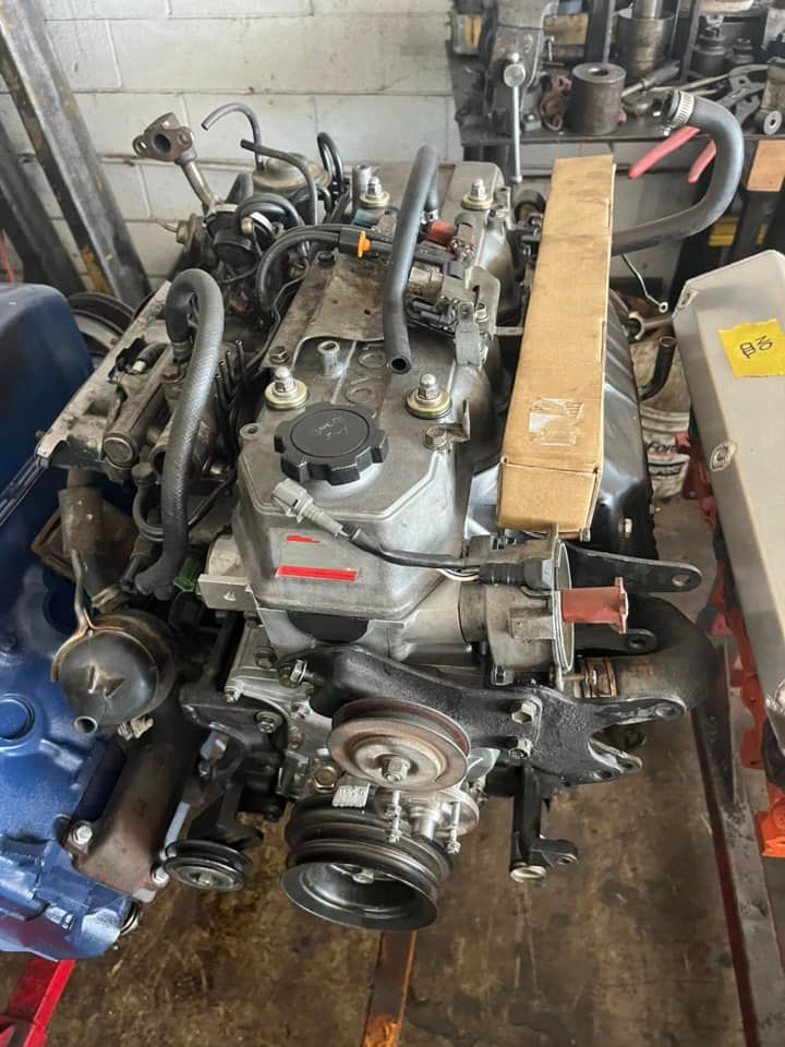 A diesel engine is sitting on top of a wooden table in a garage.