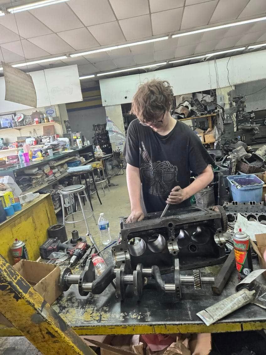 A young man is working on a car engine in a garage.