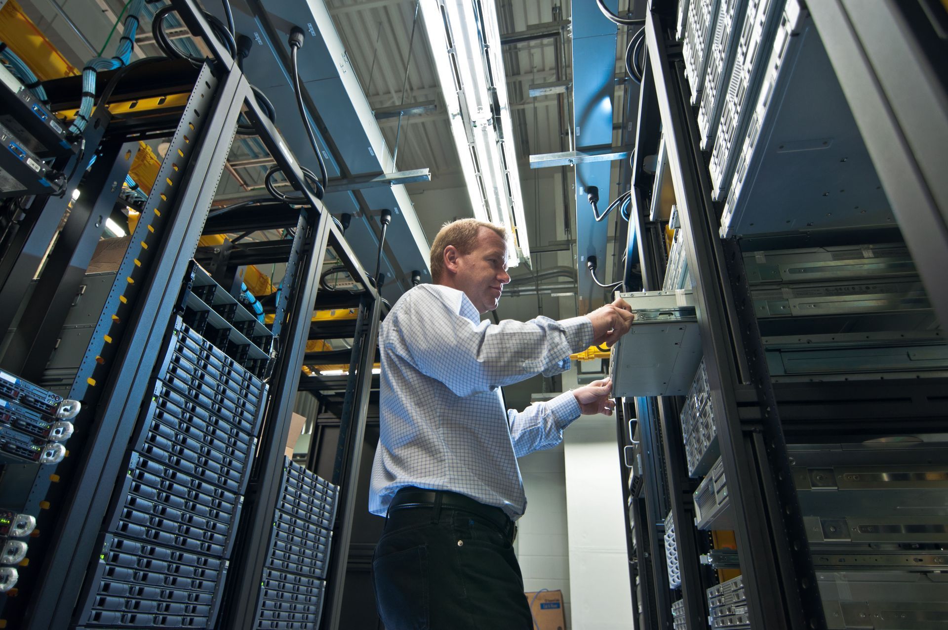Technician working inside a server rack aisle in a data center