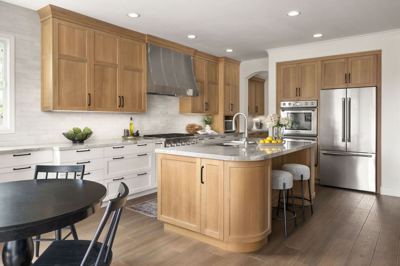 Bright kitchen with wood cabinets, stainless steel appliances, and a marble island with seating.