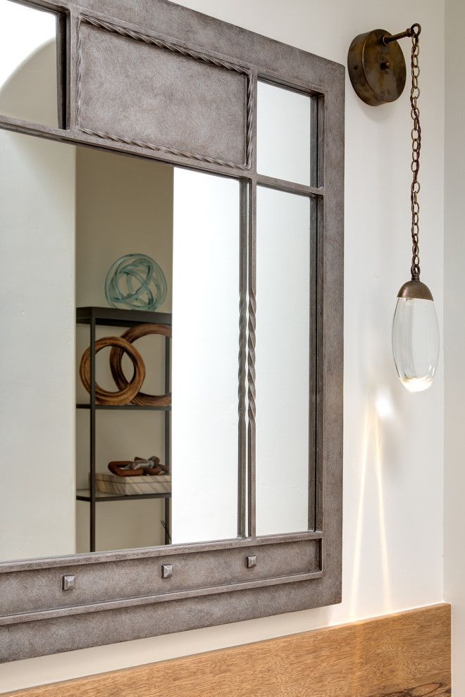 Rustic wall mirror beside a hanging bulb and wooden bench in a bright room