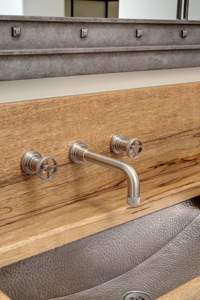 Wooden panel with a chrome faucet and two knobs mounted in front of a cushioned seat.