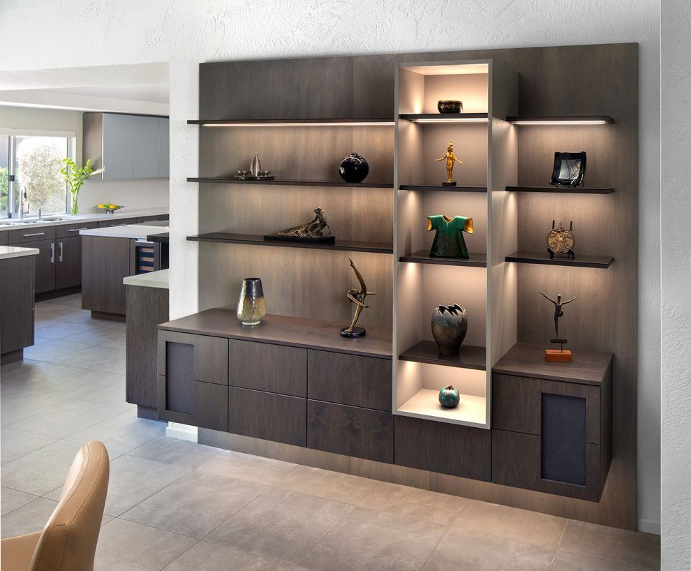 Modern built-in living room shelving with dark wood cabinets and decorative objects, softly lit