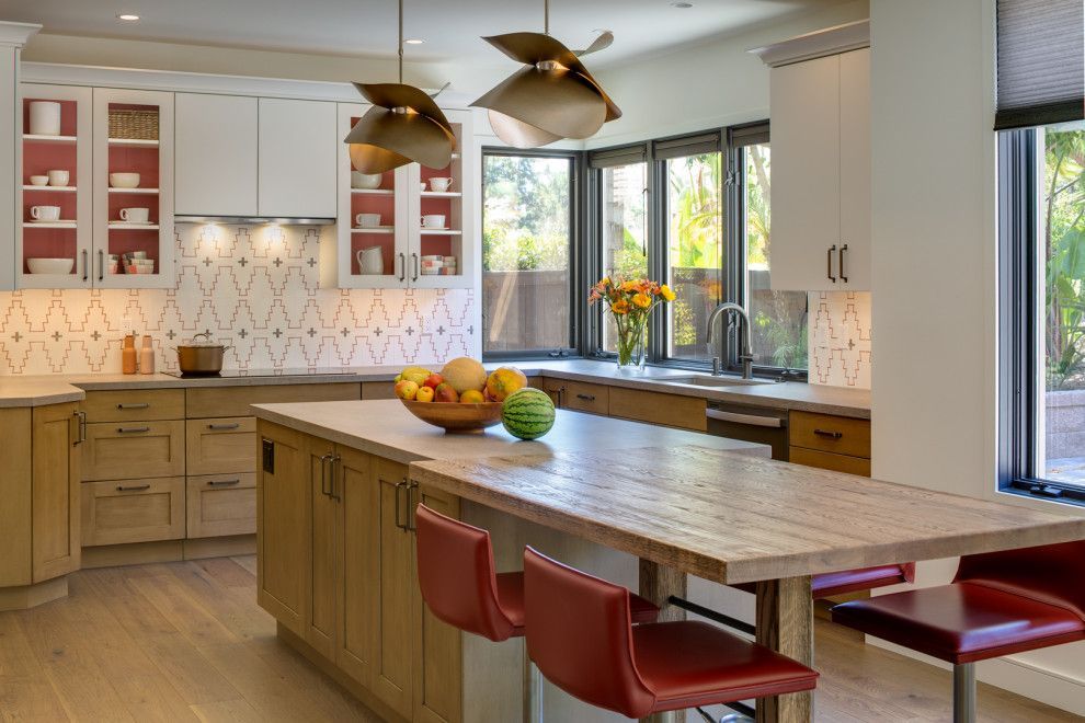 Modern kitchen with wood island, red stools, white cabinets, and large windows