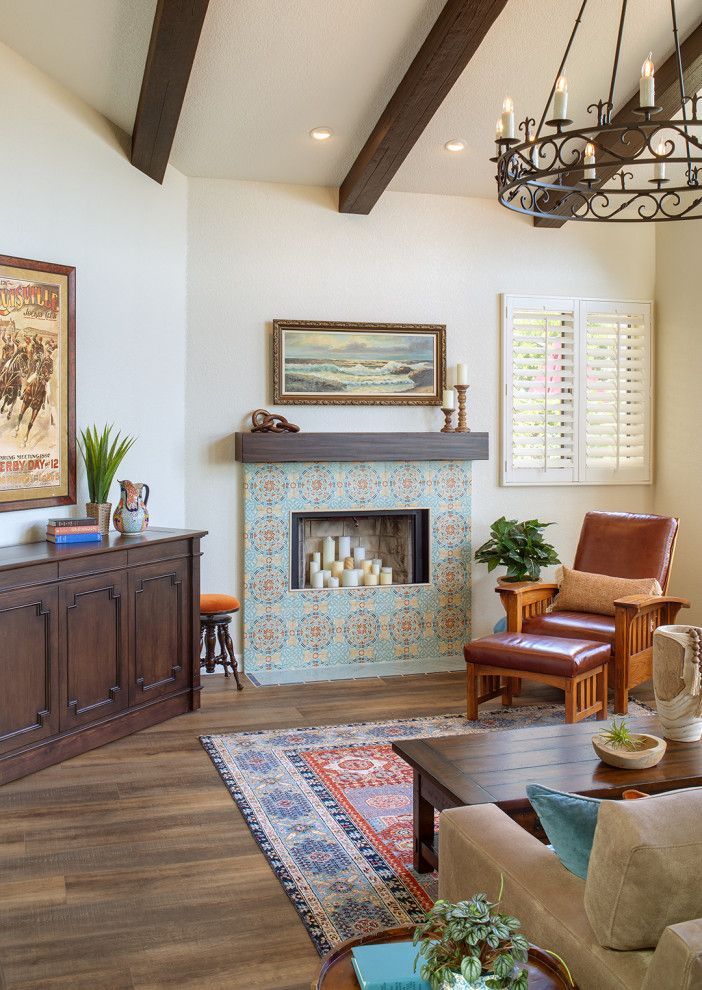 Elegant living room with a fireplace, patterned rug, wooden beams, and a chandelier.