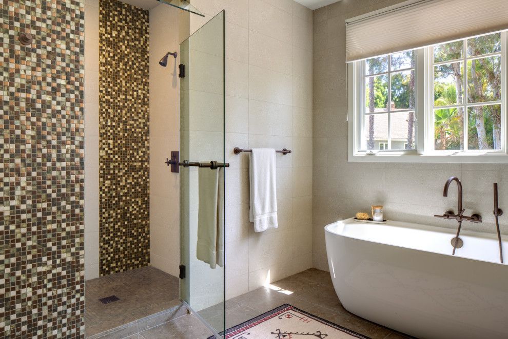 Modern bathroom with glass shower, mosaic tile, bathtub under window, and towel rack