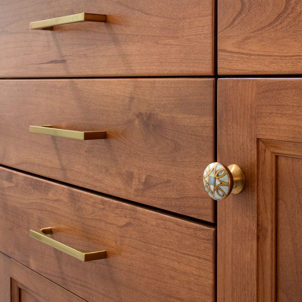 Wooden dresser with brass handles and a decorative knob on a cabinet door.