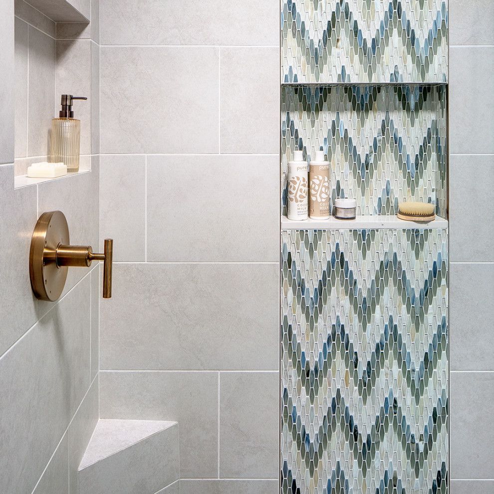 Modern shower with brass fixtures and a recessed shelf with zigzag blue and white tile accents
