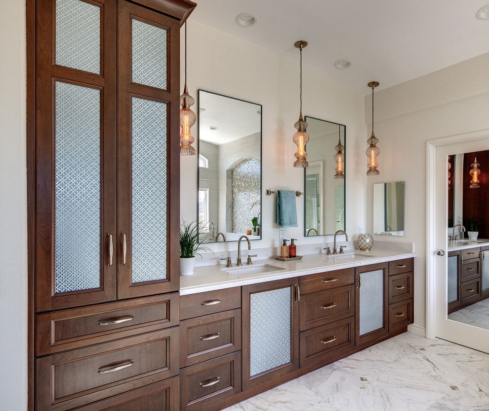 Luxurious double vanity bathroom with dark wood cabinets, white countertops, mirrors, and pendant lights