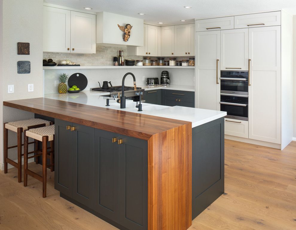 Modern kitchen with white cabinets, dark island with wood countertop, and hardwood floors