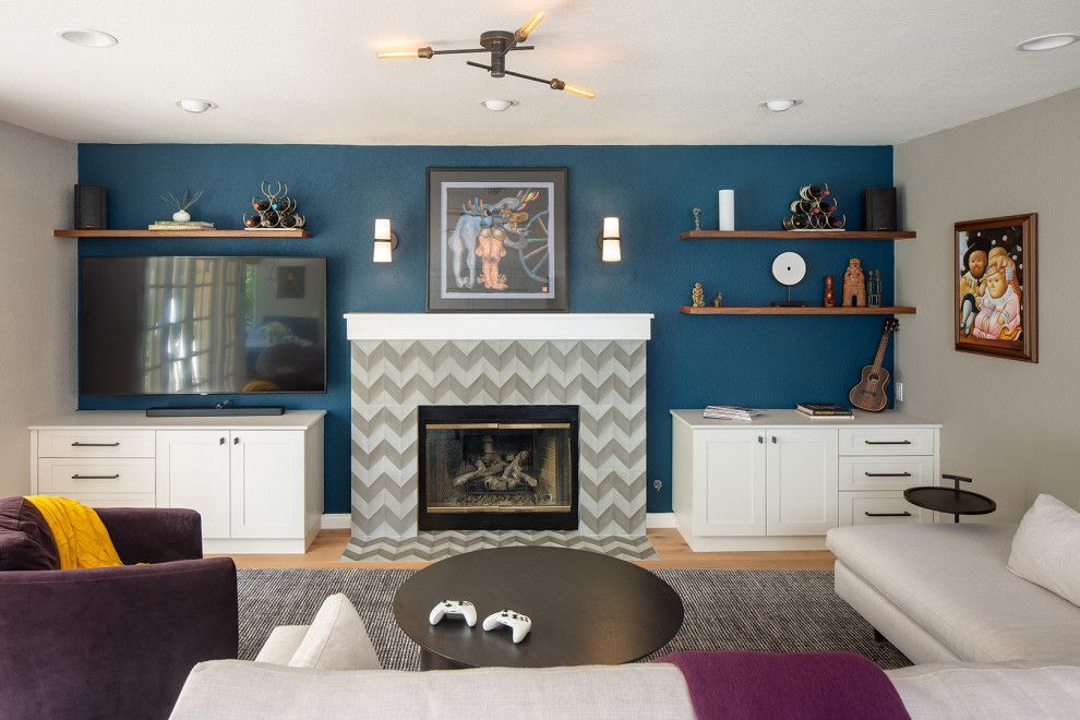 Modern living room with blue accent wall, fireplace, TV, built-in shelves, and white cabinets