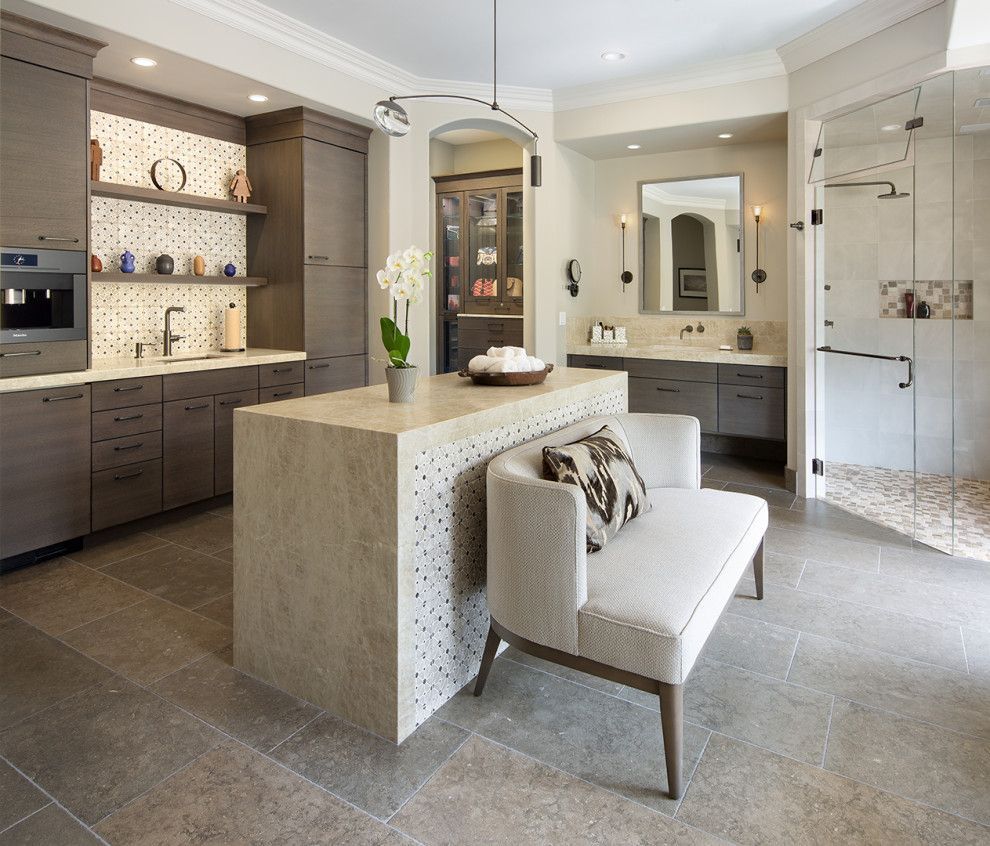 Modern bathroom with stone vanity island, glass shower, double sinks, and a cushioned bench chair