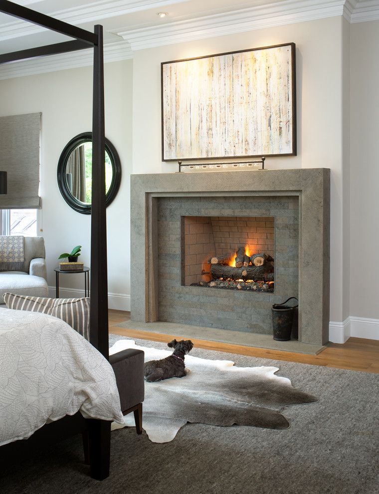 Modern bedroom with a lit fireplace, gray rug, and framed abstract art above the mantel