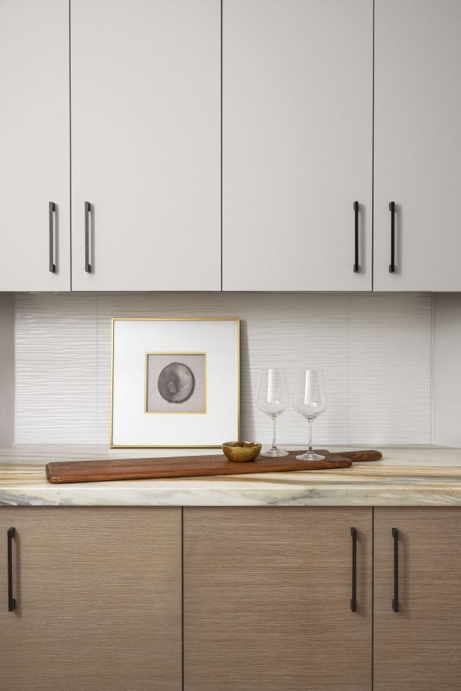 Modern kitchen cabinets with a countertop, framed art, and two wine glasses on a tray.