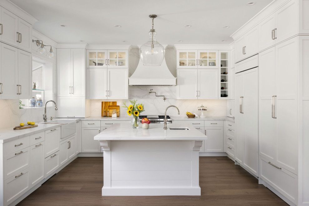 Bright white modern kitchen with large island, stainless range hood, and flowers on the counter