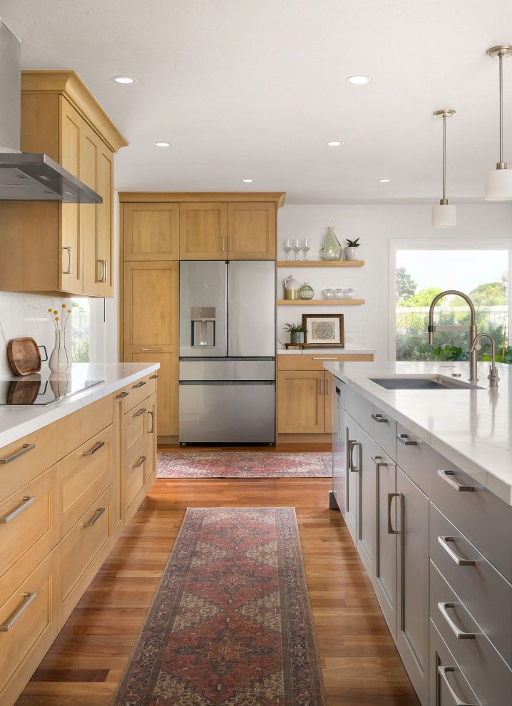Bright kitchen with wood cabinets, stainless fridge, long island, and patterned runner rug.