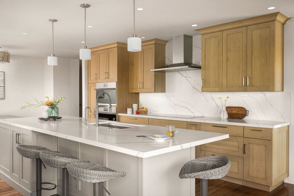 Bright modern kitchen with wood cabinets, white island, pendant lights, and gray barstools